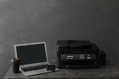 Photo of New modern printer, smartphone and laptop on grey table
