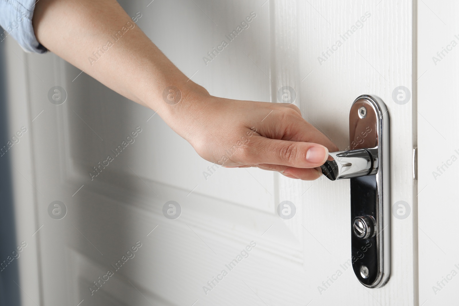 Photo of Woman opening white wooden door indoors, closeup