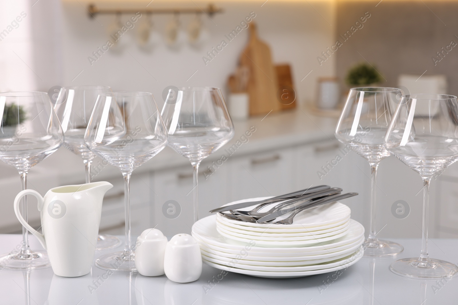 Photo of Set of clean dishware, glasses and cutlery on table in kitchen