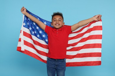 4th of July - Independence Day of USA. Happy boy with American flag on light blue background