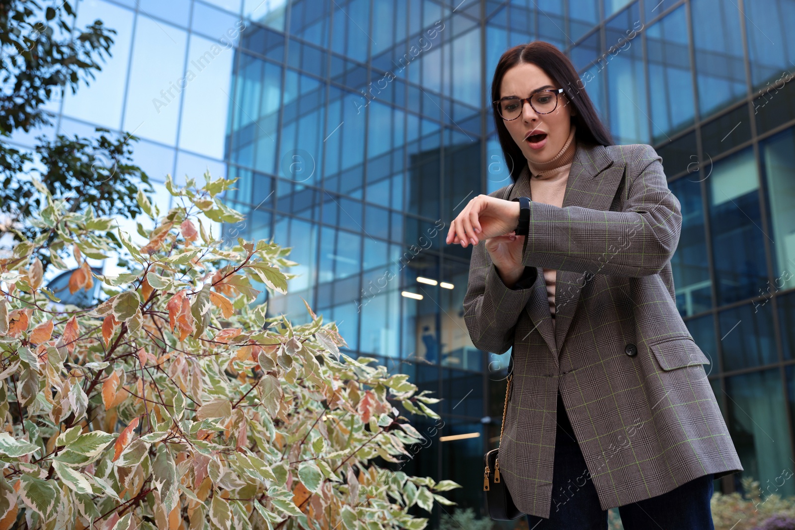 Photo of Emotional woman checking time on watch outdoors. Being late concept