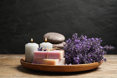 Photo of Burning candles, stones, soap bars and lavender flowers on wooden table