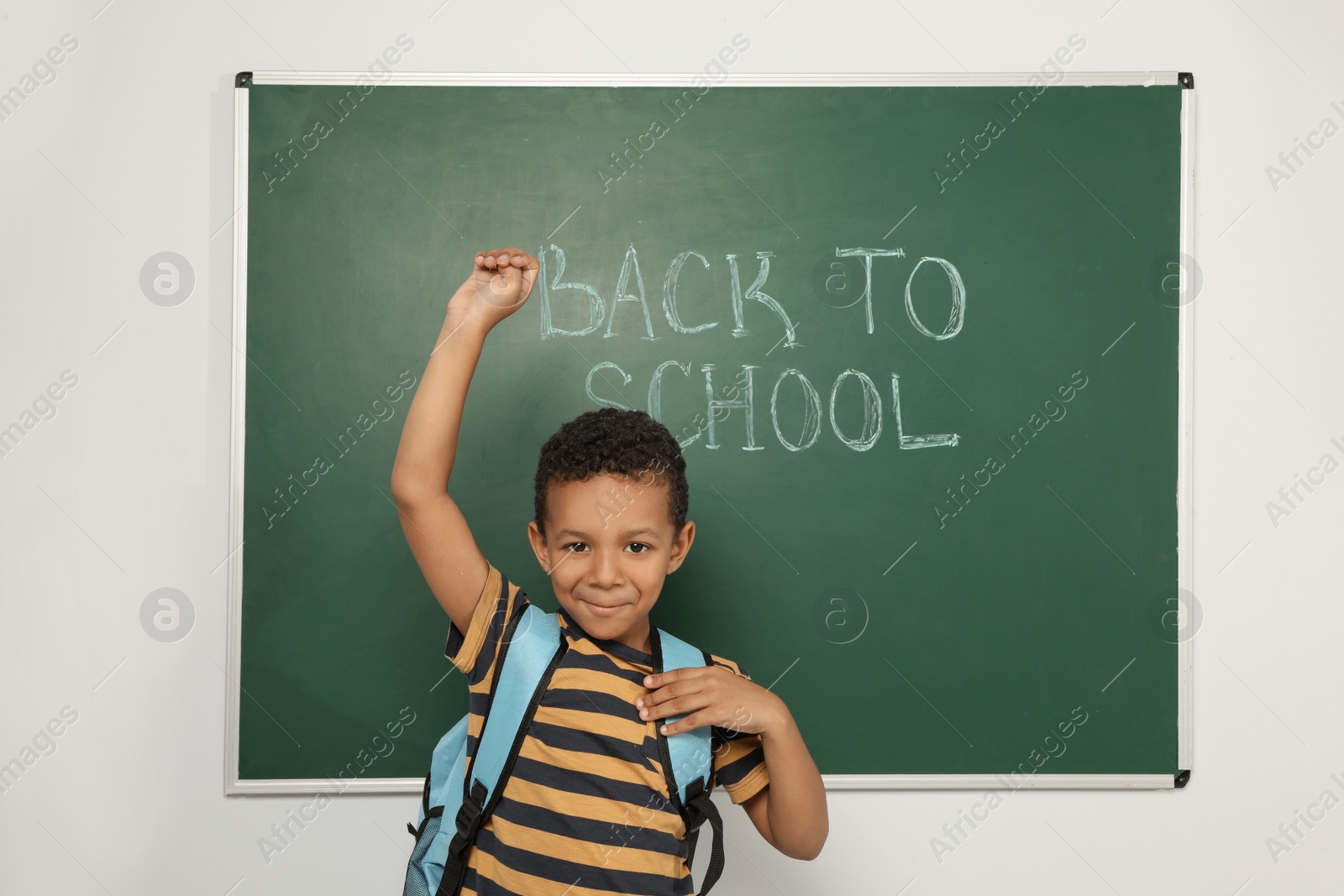 Photo of Little African-American child near chalkboard with text BACK TO SCHOOL