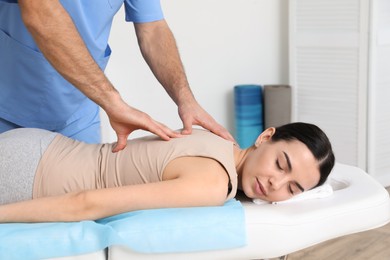 Photo of Orthopedist massaging young woman's back in clinic, closeup. Scoliosis treatment