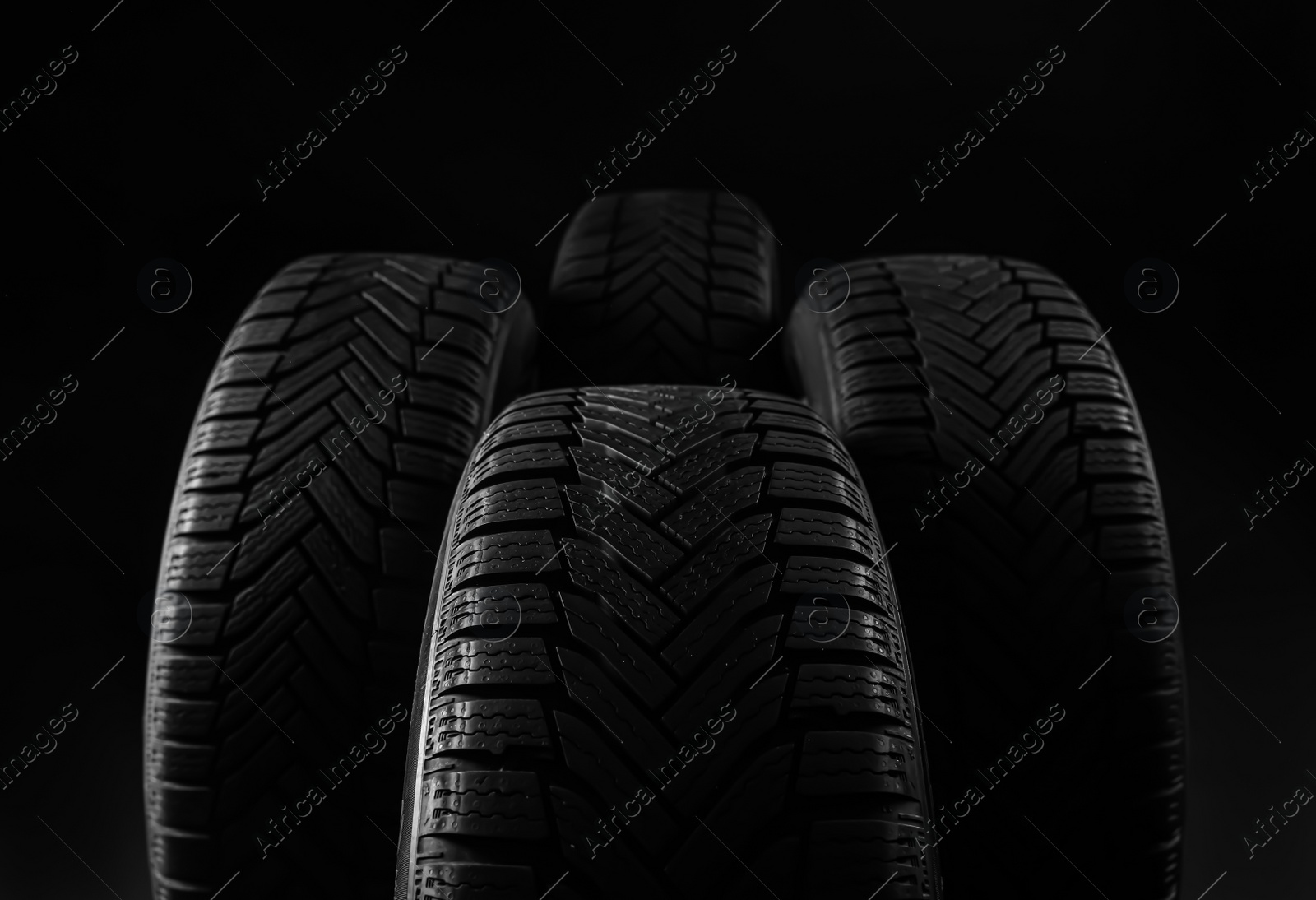 Photo of Set of new winter tires on black background, closeup