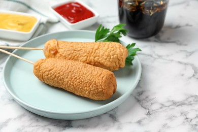 Photo of Delicious deep fried corn dogs and sauces on white marble table