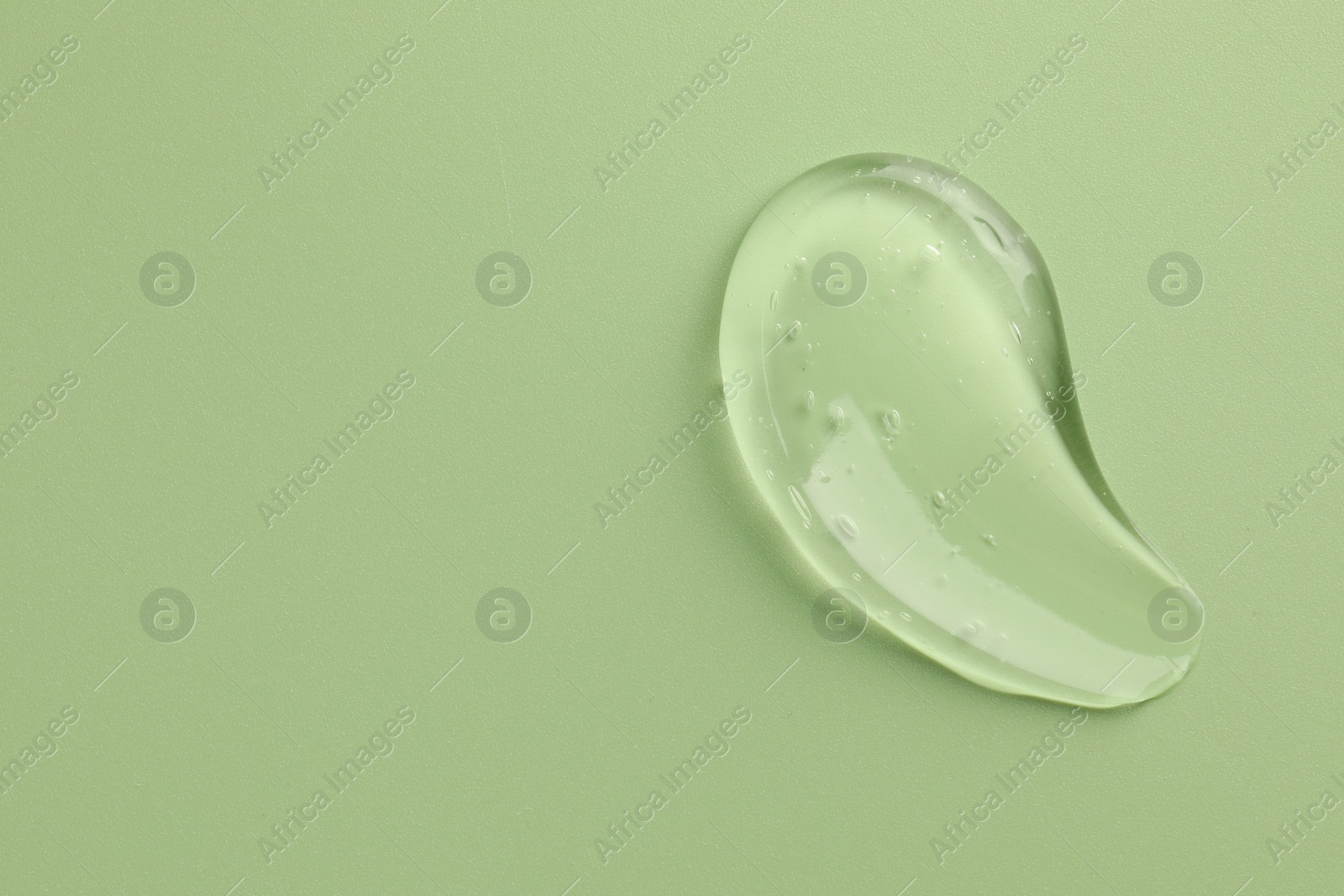 Photo of Smear of clear cosmetic gel on light green background, top view. Space for text