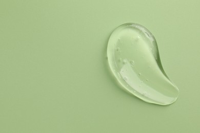 Smear of clear cosmetic gel on light green background, top view. Space for text