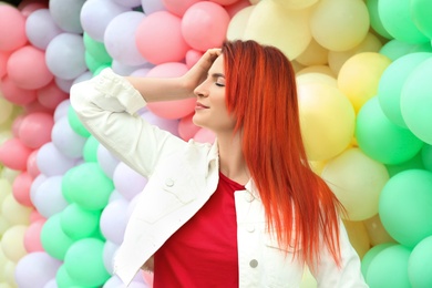 Photo of Young woman with bright dyed hair near colorful balloons