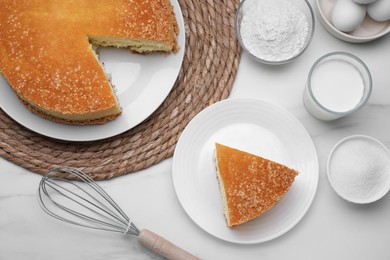 Tasty sponge cake, milk and ingredients on white marble table, flat lay