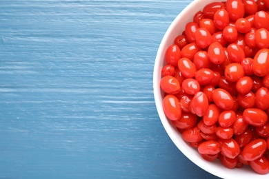 Photo of Fresh ripe goji berries in bowl on blue wooden background, top view. Space for text