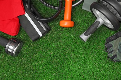 Photo of Different sports equipment on green grass, flat lay. Space for text