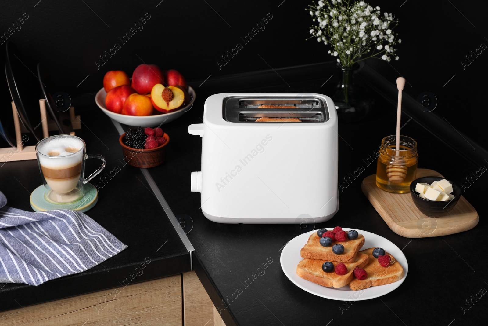 Photo of Modern toaster with bread, honey and fresh berries on countertop in kitchen