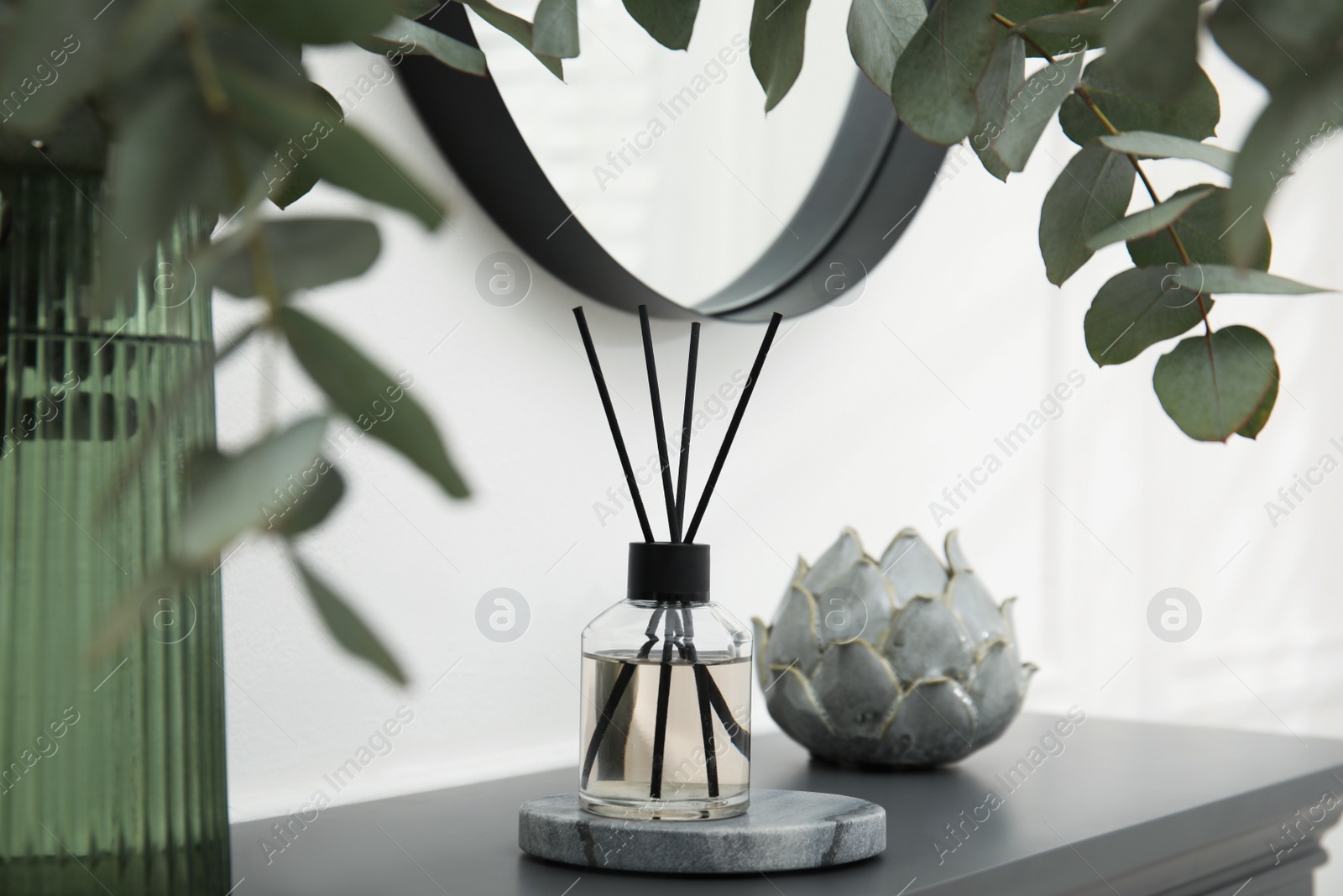 Photo of Reed diffuser and home decor on grey table near white wall