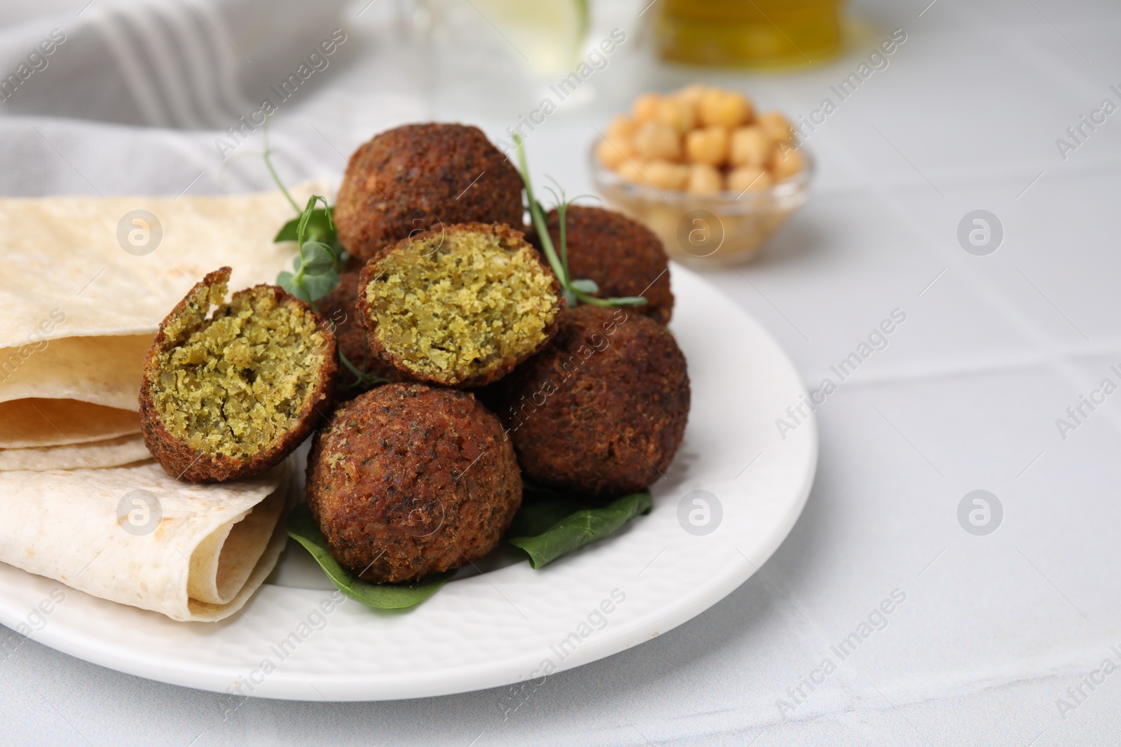 Photo of Delicious falafel balls, herbs and lavash on white table