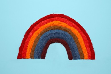 Photo of Rainbow made of different food coloring on light blue background, top view