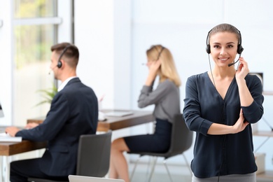 Photo of Young female receptionist with headset in office