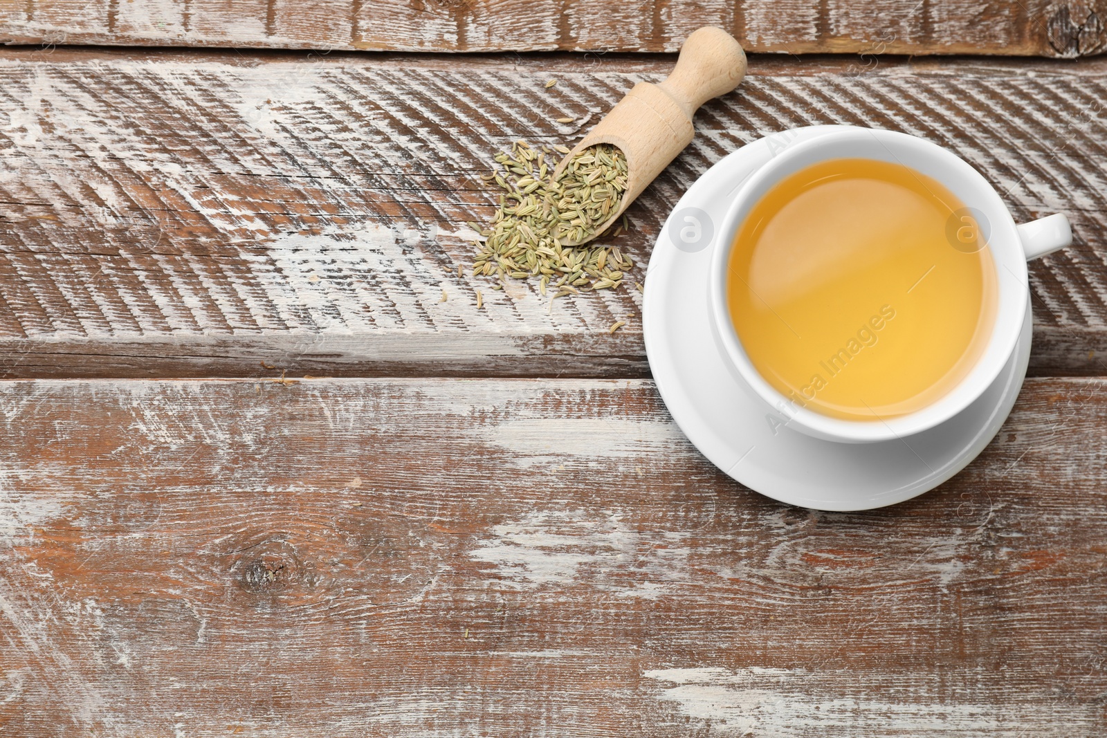 Photo of Aromatic fennel tea, seeds and scoop on wooden table, top view. Space for text