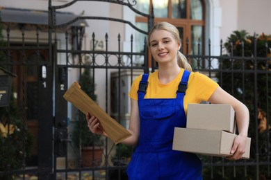 Courier in uniform holding different parcels outdoors