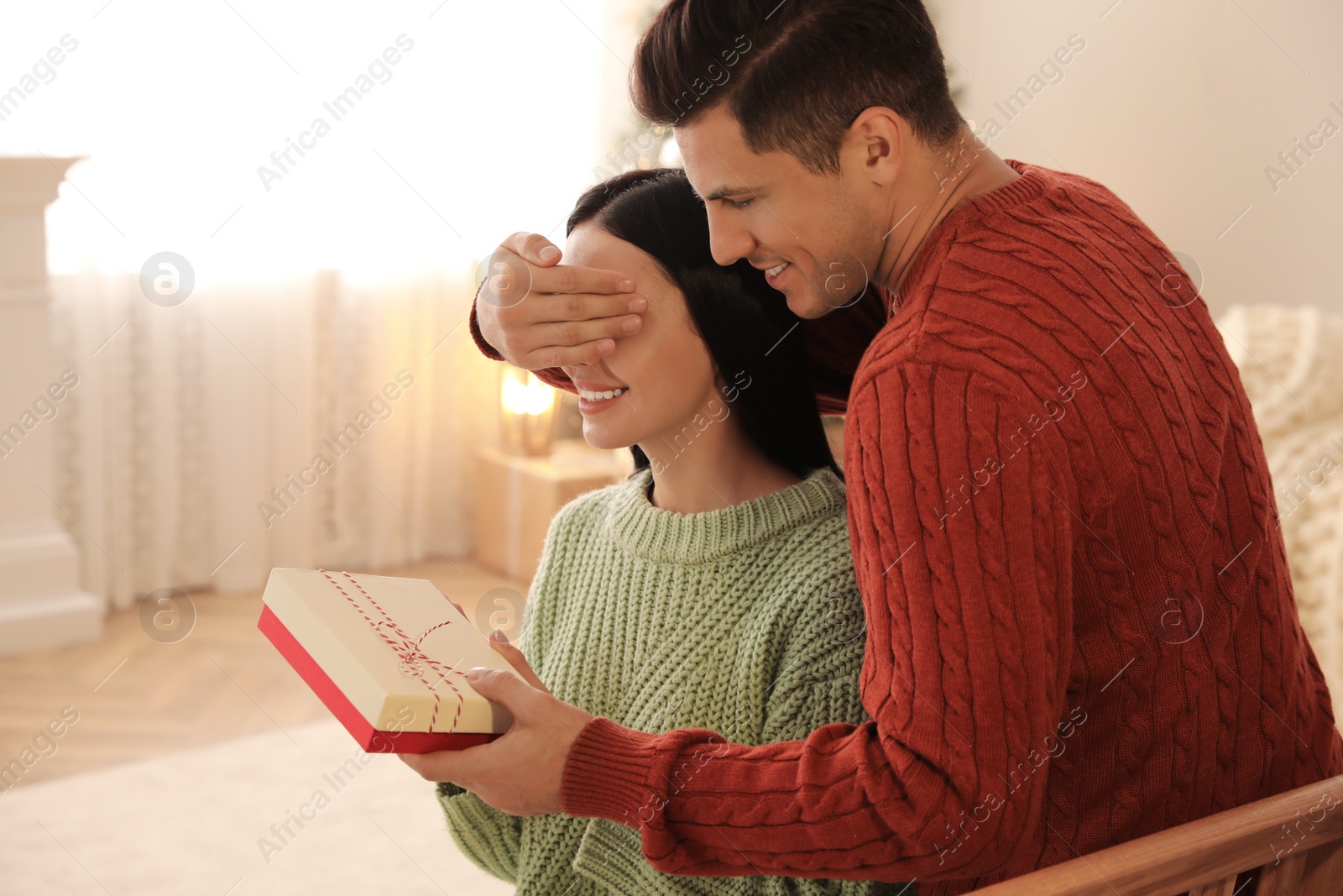 Photo of Boyfriend giving Christmas gift box to his girlfriend at home