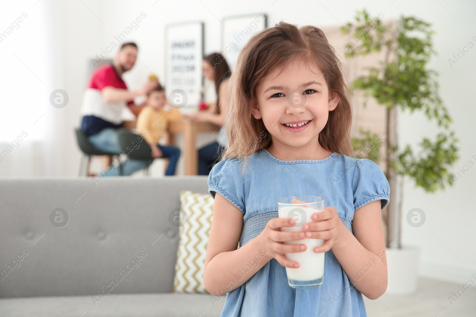 Photo of Cute little girl with glass of milk at home