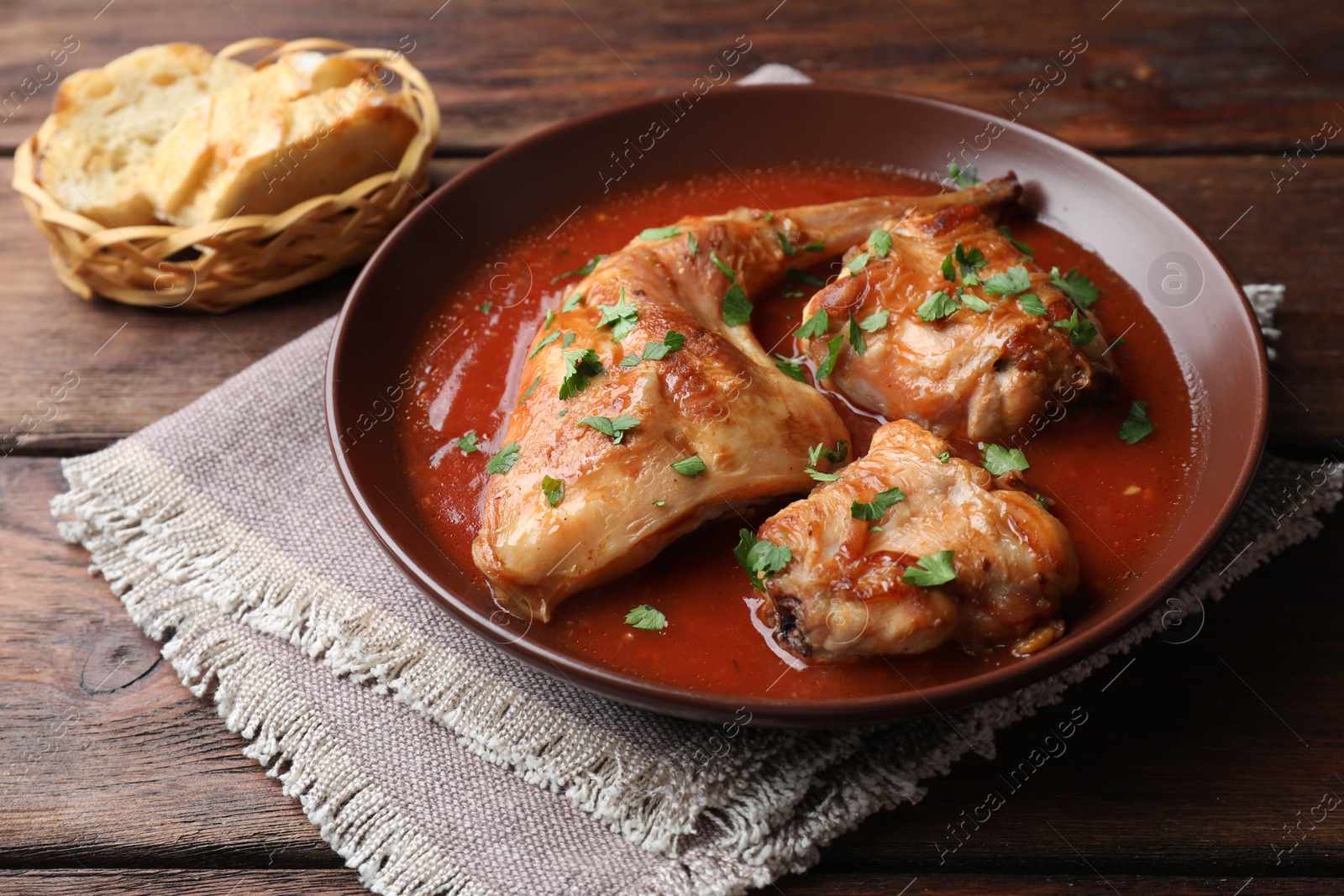 Photo of Tasty cooked rabbit meat with sauce and bread on wooden table