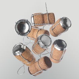 Image of Many corks of sparkling wine bottles falling on light grey background