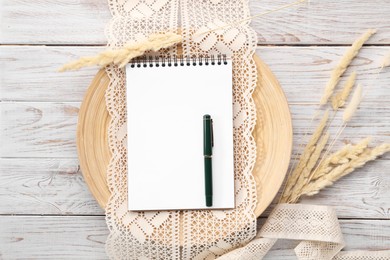 Photo of Guest list. Notebook, pen, spikelets and lace ribbons on wooden background, flat lay