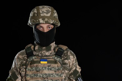 Photo of Soldier in Ukrainian military uniform on black background. Space for text