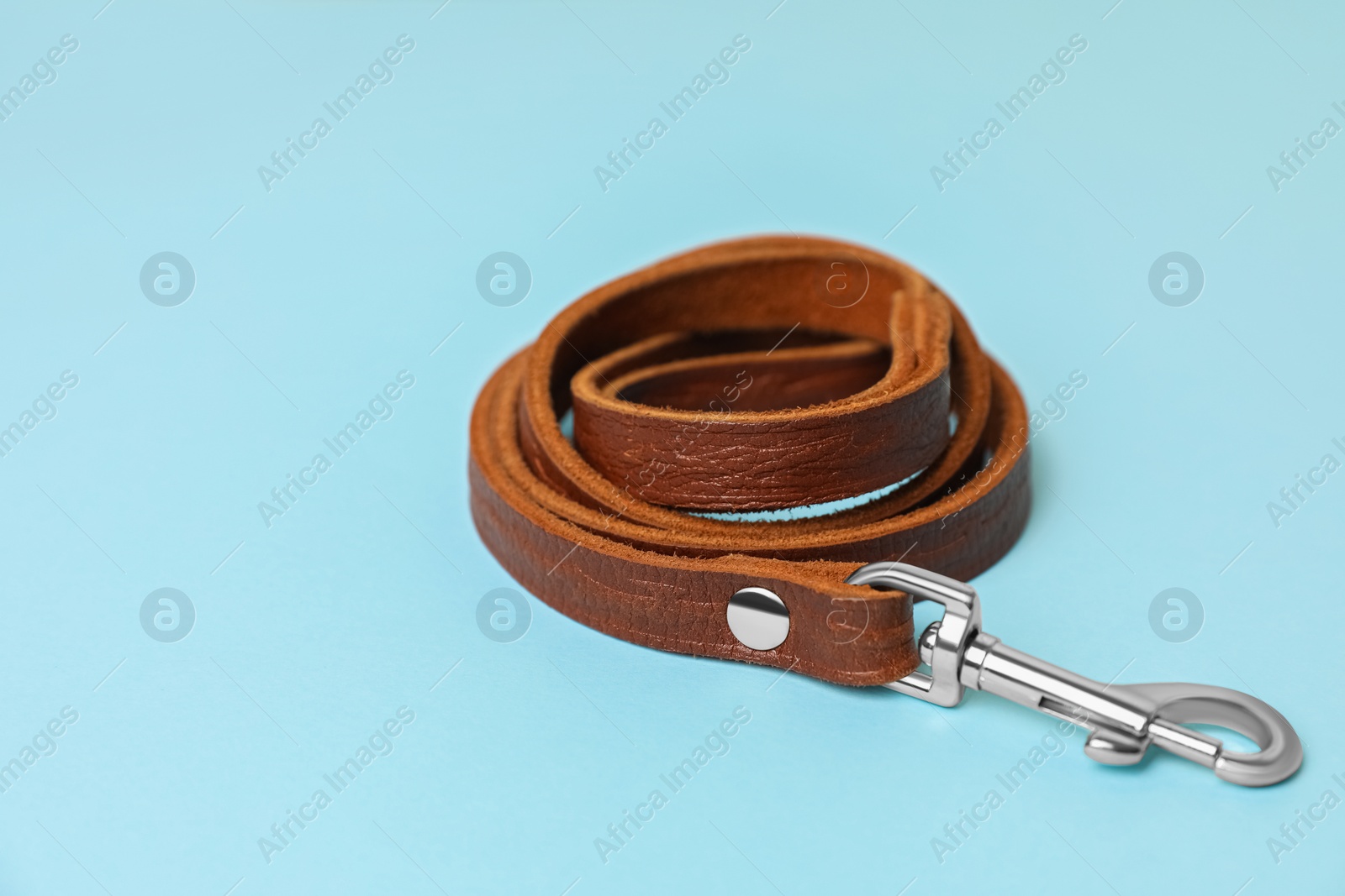 Photo of Brown leather dog leash on light blue background, closeup. Space for text