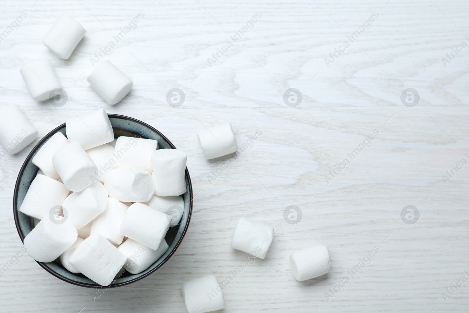 Photo of Delicious puffy marshmallows on white wooden table. Space for text