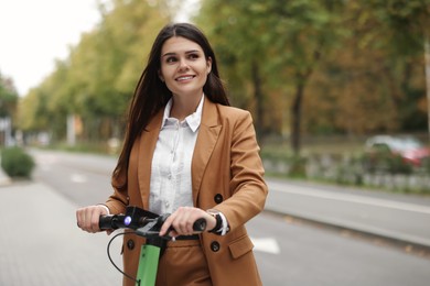 Businesswoman with modern electric kick scooter on city street