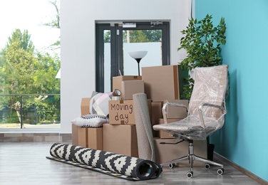 Cardboard boxes and household stuff in empty room. Moving day