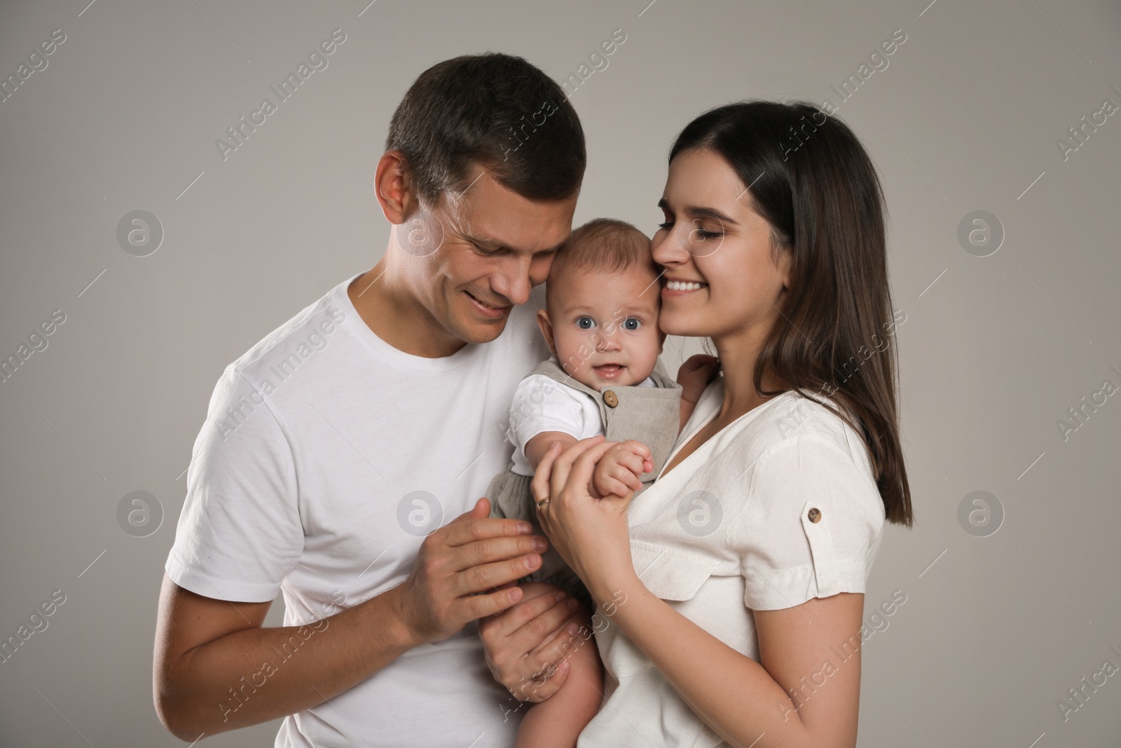 Photo of Happy family. Couple with their cute baby on grey background