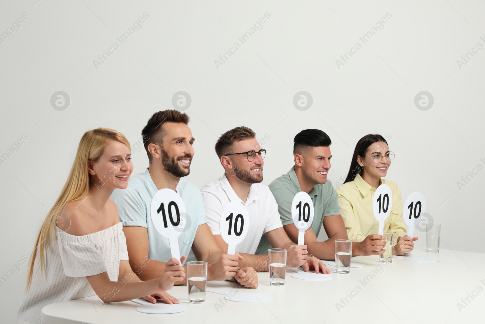 Photo of Panel of judges holding signs with highest score at table on white background