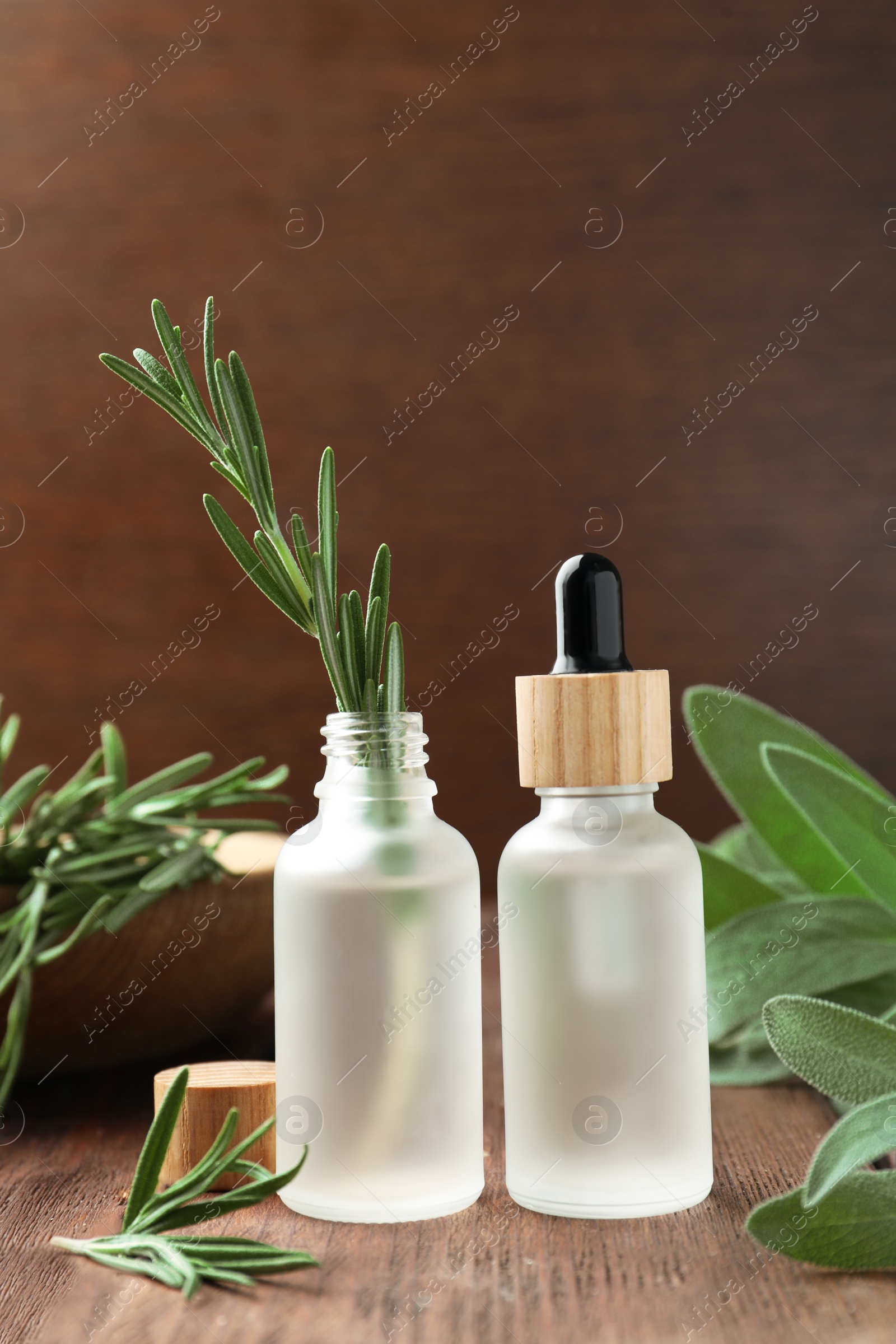 Photo of Bottles of essential oils and fresh herbs on wooden table, space for text