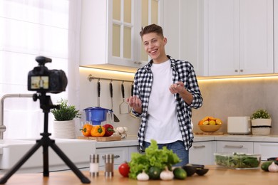 Smiling food blogger explaining something while recording video in kitchen