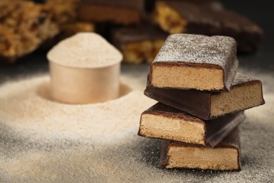 Tasty energy bars and protein powder on table, closeup. Space for text