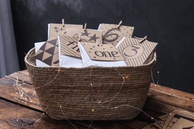 Many gift bags in wicker basket and garland on wooden table. Advent calendar