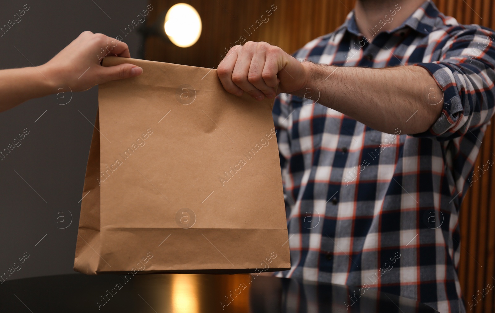 Photo of Man giving paper bag with order to customer in cafe, closeup. Mock up for design