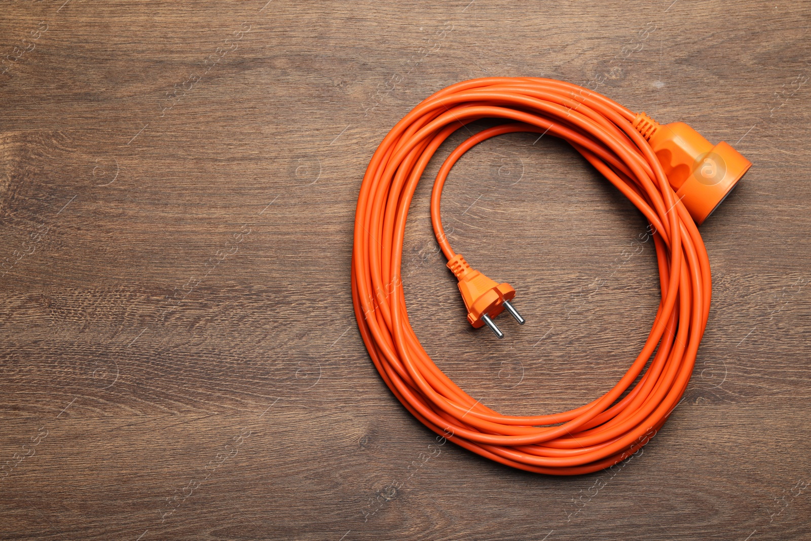 Photo of Extension cord on wooden floor, top view. Space for text