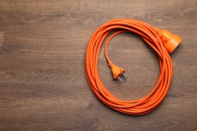 Photo of Extension cord on wooden floor, top view. Space for text
