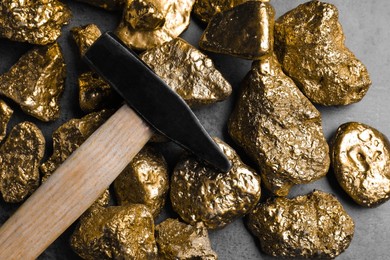 Photo of Gold nuggets and hammer on grey table, flat lay