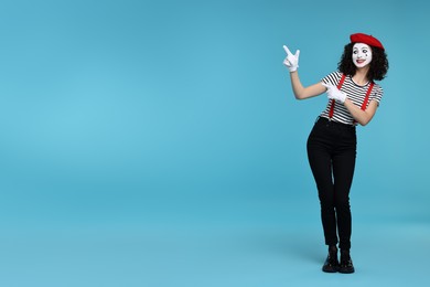 Funny mime with beret posing on light blue background, space for text