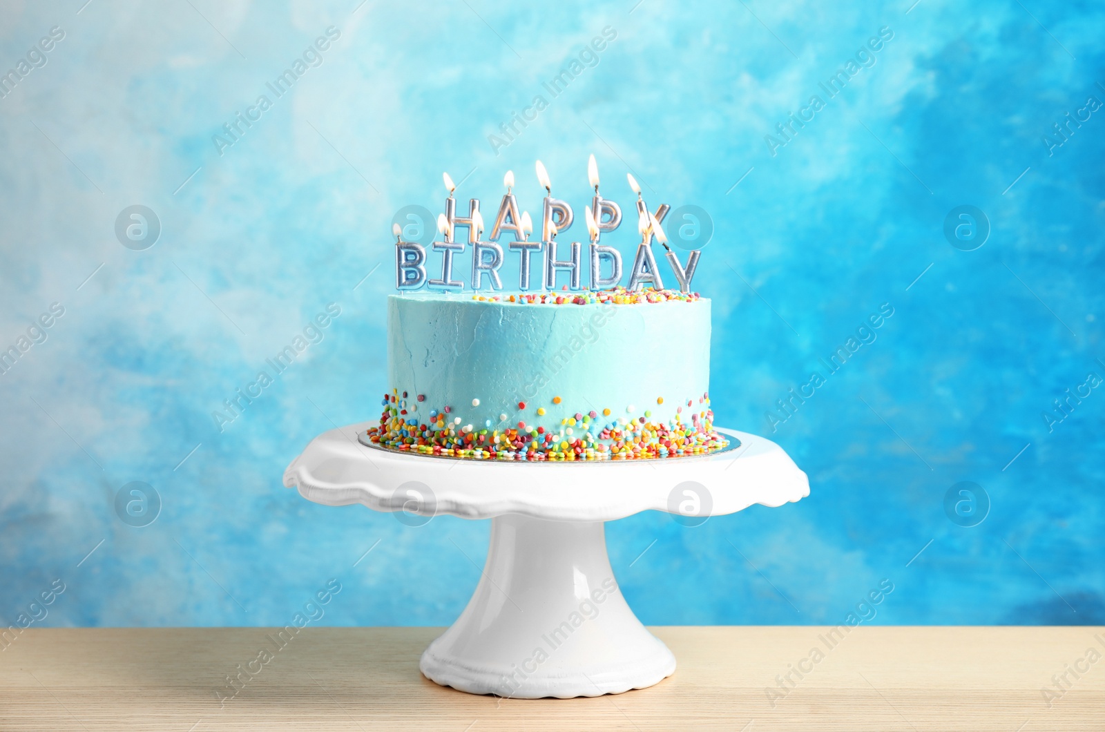 Photo of Fresh delicious birthday cake with candles on stand against color background