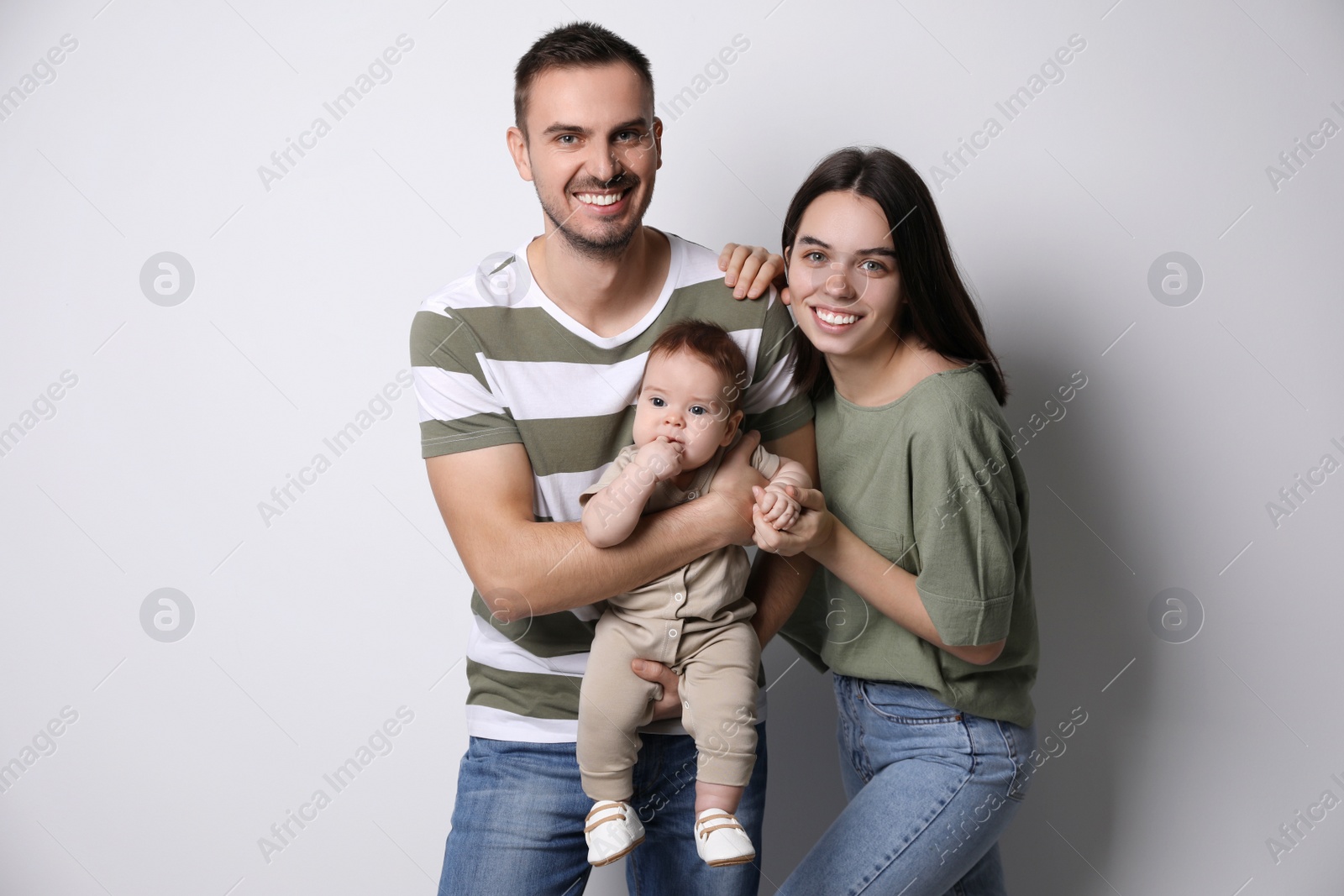 Photo of Happy family. Couple with their cute baby on grey background