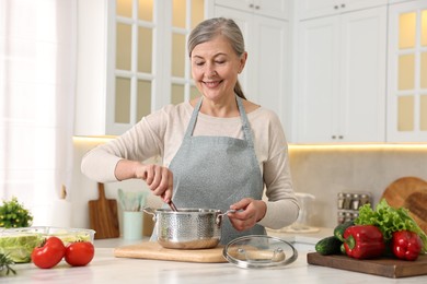 Photo of Happy housewife cooking at table in kitchen