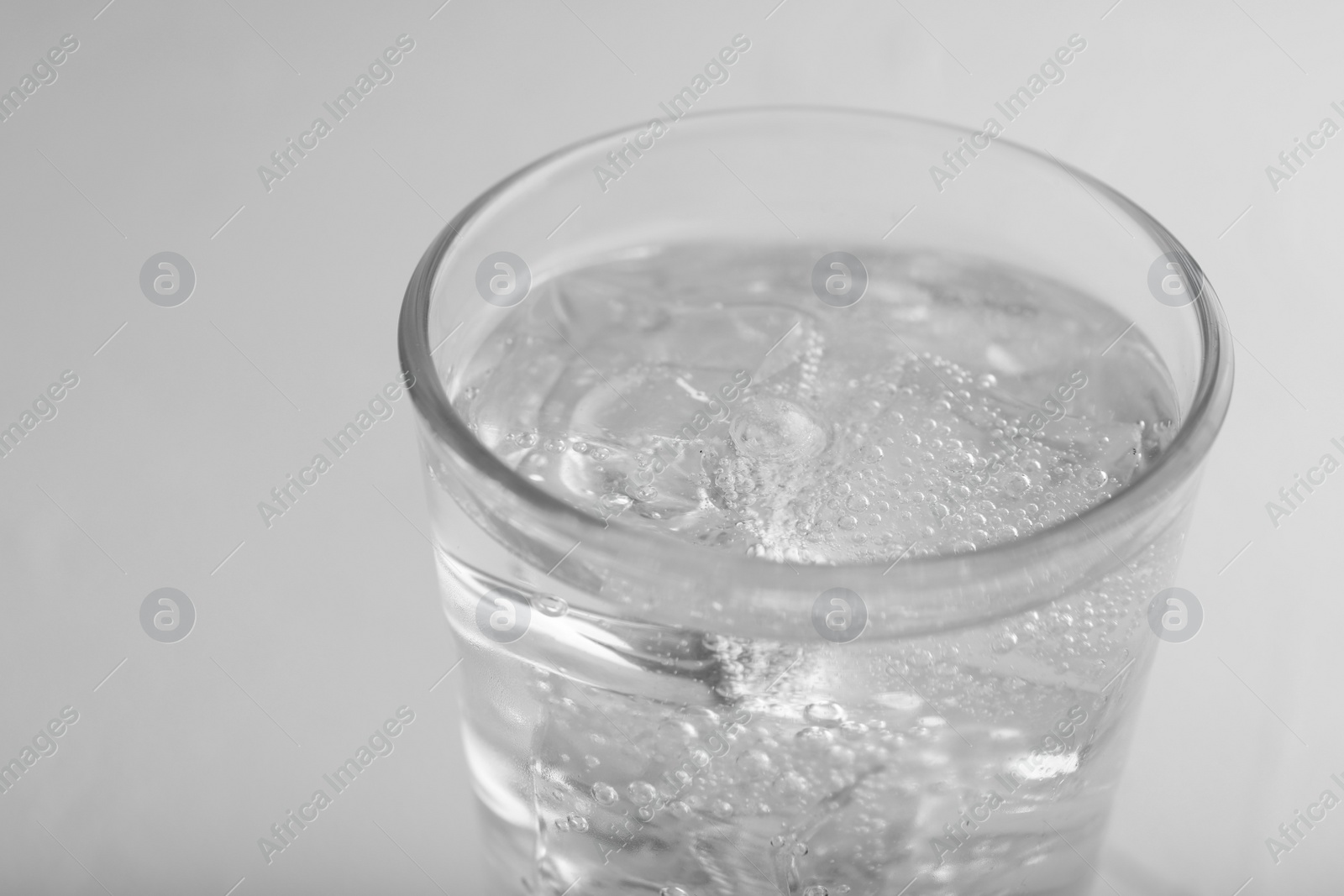 Photo of Glass of soda water on light grey table, closeup