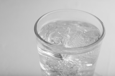 Photo of Glass of soda water on light grey table, closeup