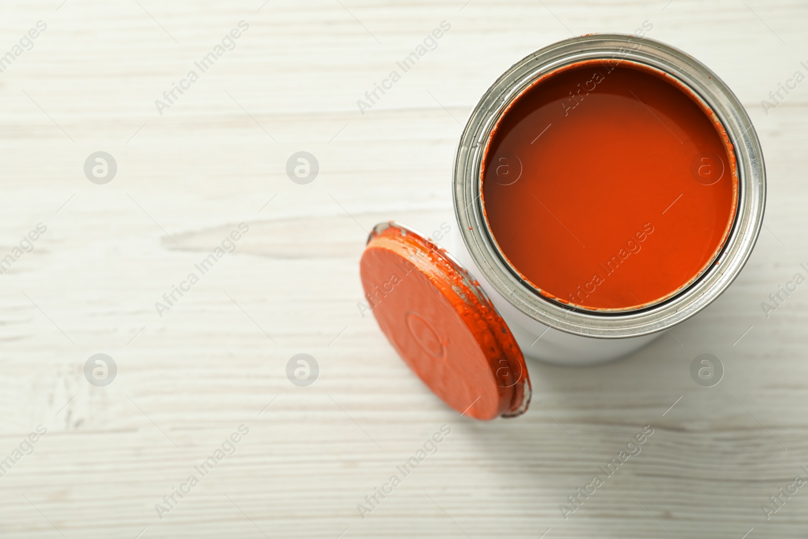 Photo of Can of orange paint on white wooden table, top view. Space for text